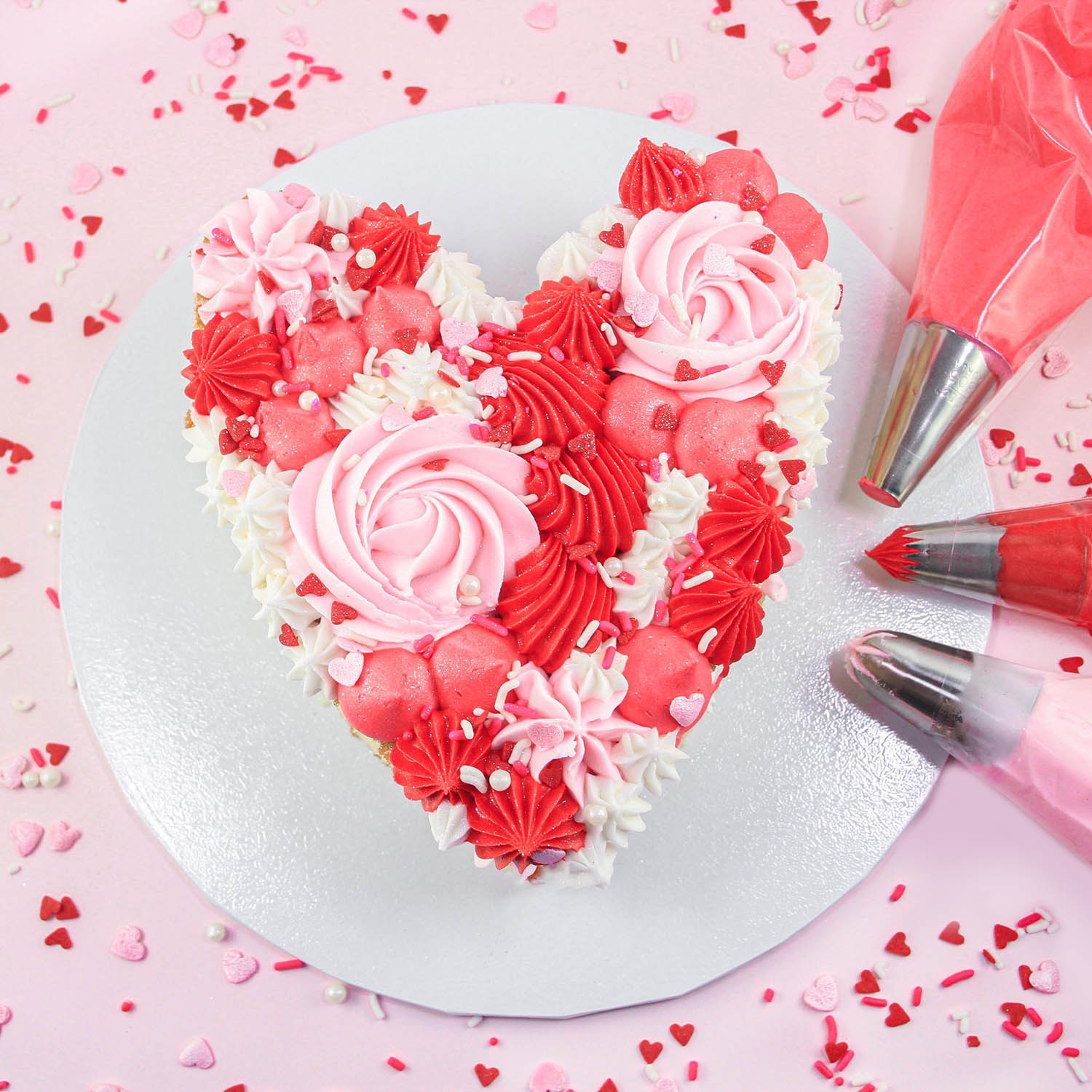 Heart shaped cake piped with red, pink, white buttercream