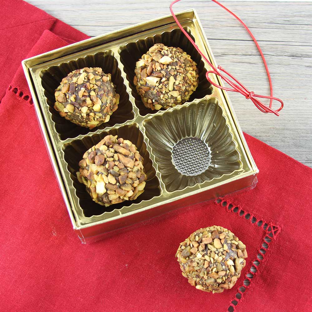 Pistachio ganache truffles in an opened candy box.