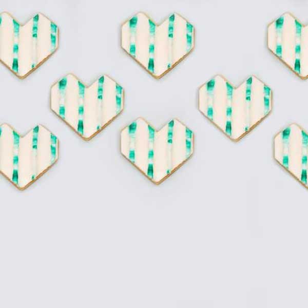 geometric heart cookie decorated with buttercream and inset stripes of green buttercream..