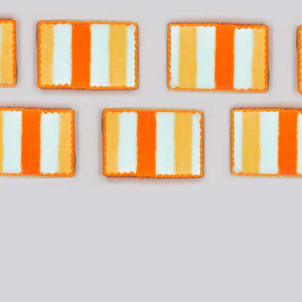 Rectangle cookies decorated with striped buttercream. Edges piped in gold.