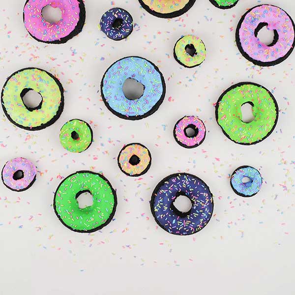 chocolate doughnuts dipped in vibrant colors of the rainbow and topped with rainblow shimmer jimmies.