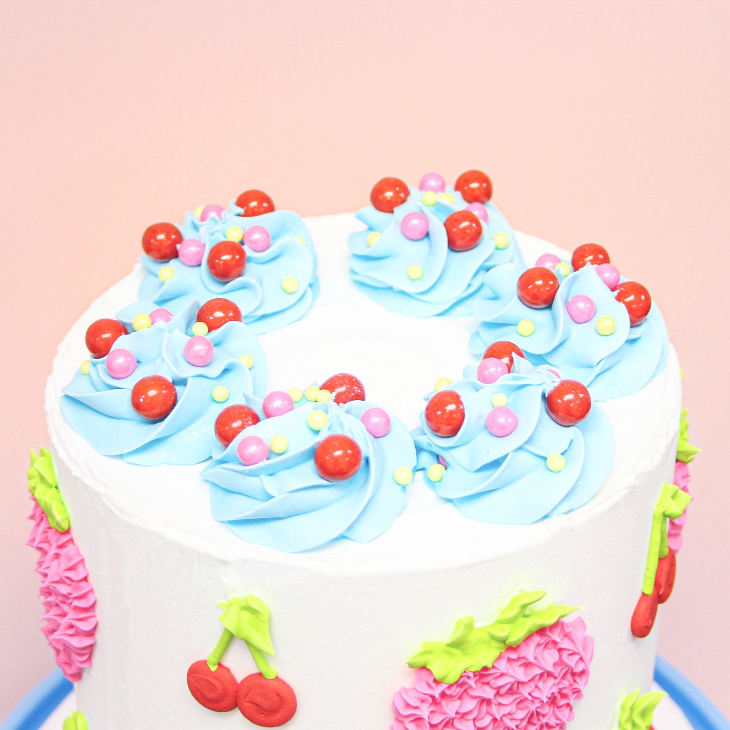 Top of this cake is covered in swirls of buttercream, sprinkles and red sugar pearls.