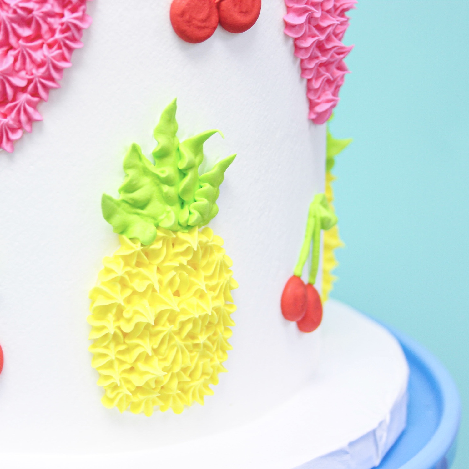 side of cake featuring a pineapple piped with a star tip.