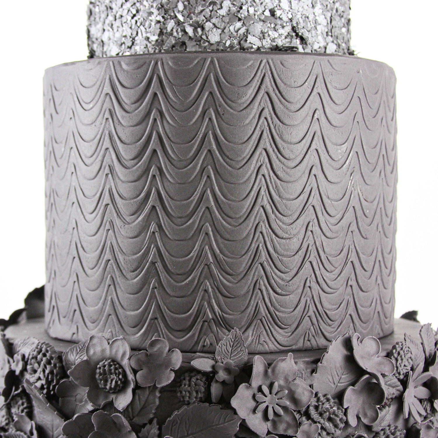 3 tiered black fondant cake. The middle tier is embossed in a fanciful wave pattern.