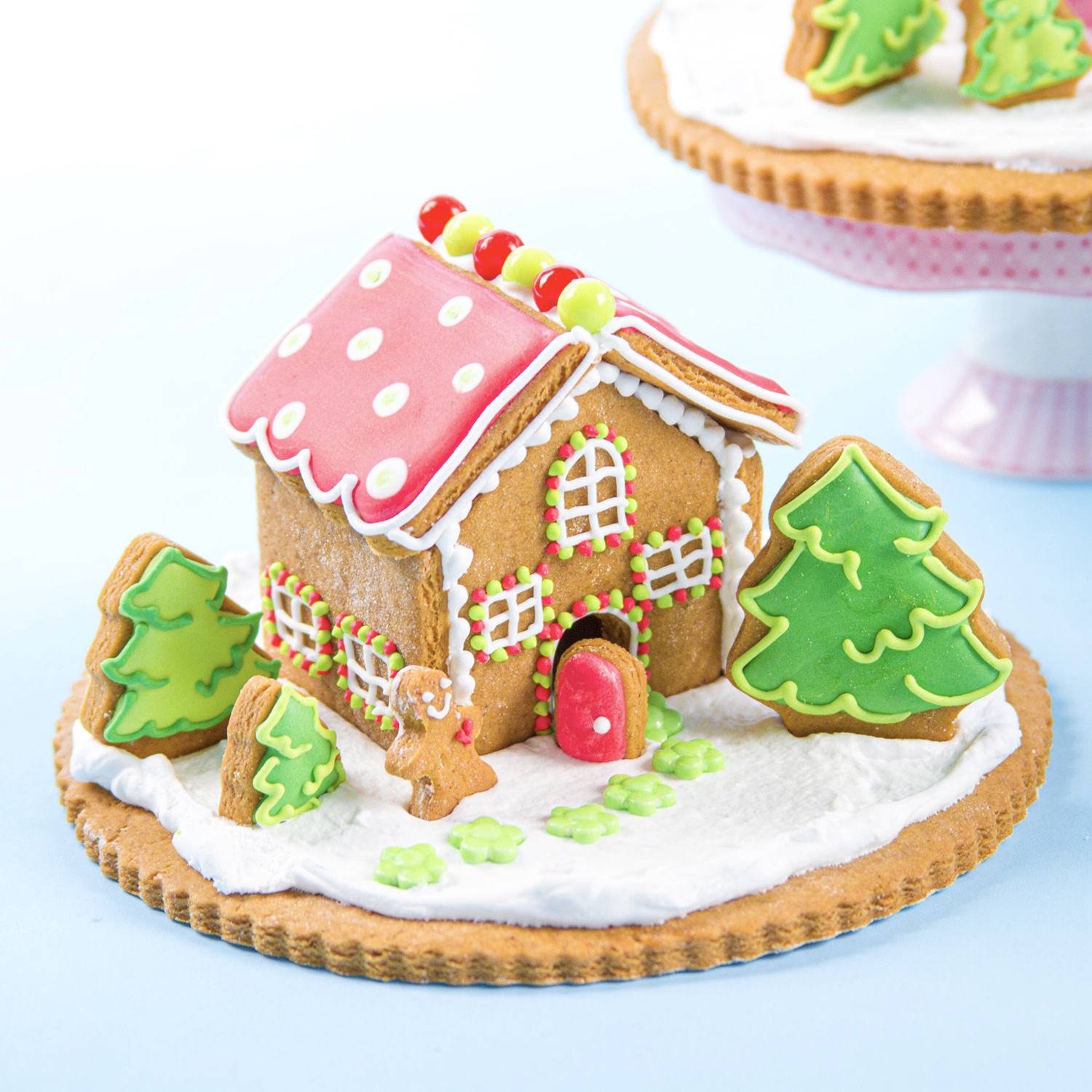 Mini edible gingerbread house scene decorated in festive red green and white royal icing.