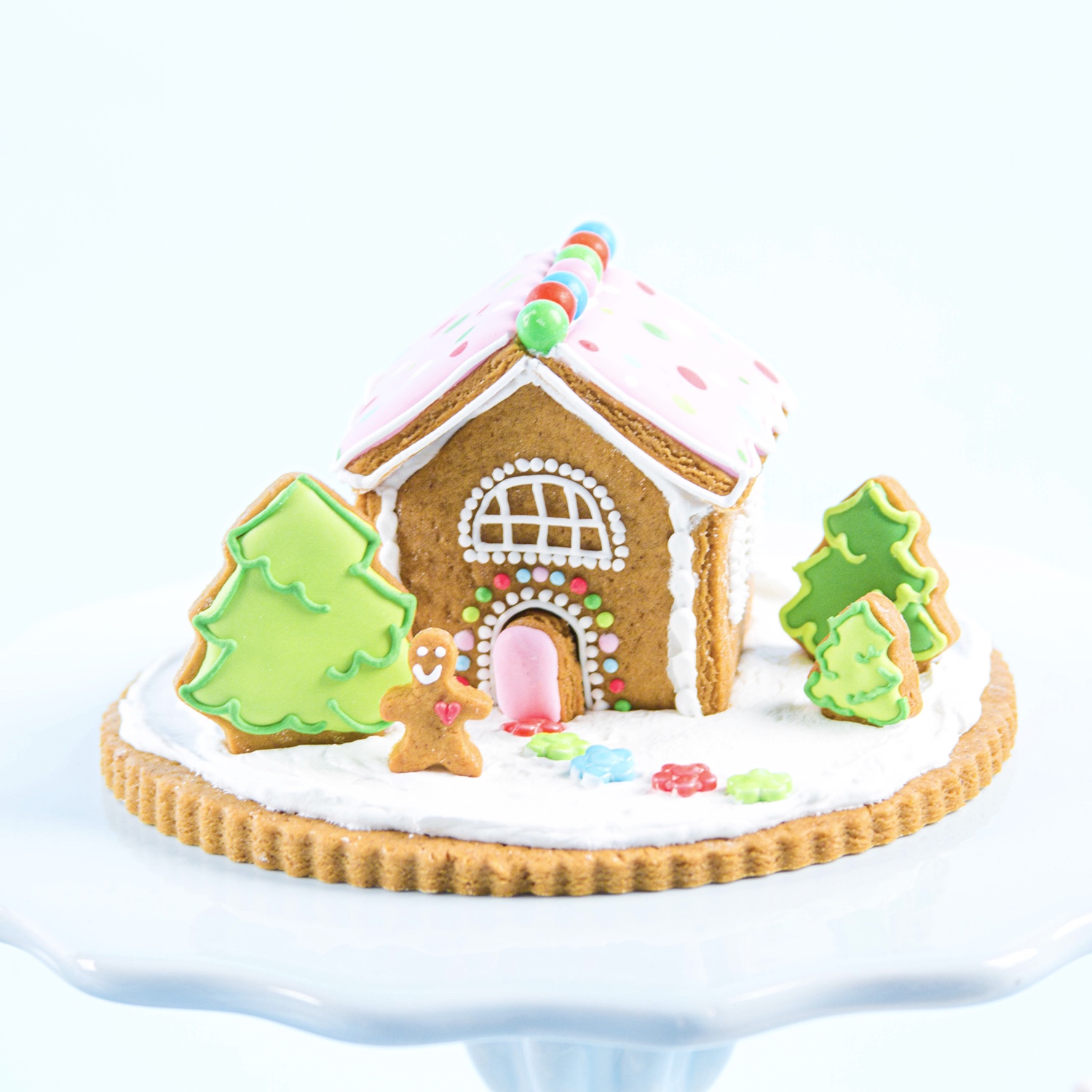 mini decorated gingerbread house decorated in pink, green and blue royal icing.