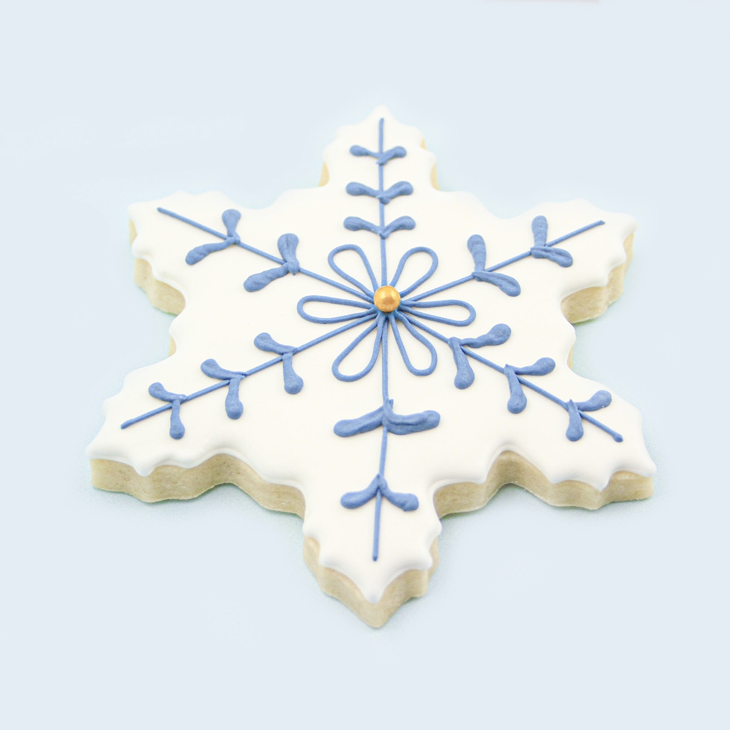 White and blue snowflake piped cookie with a gold sugar pearl in the center.