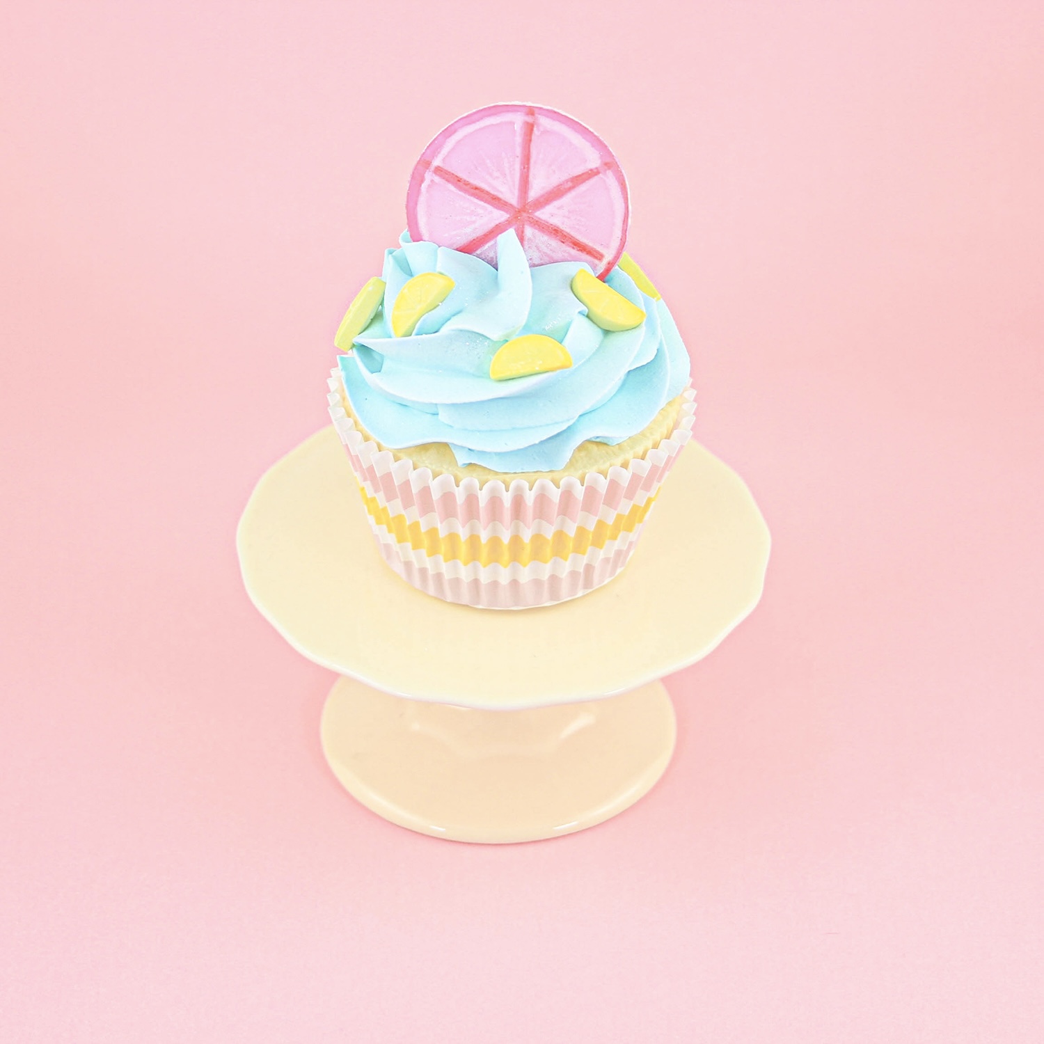 Blue swirl cupcake with a hand painted pink lemon slice fondant topper and lemon sprinkles.