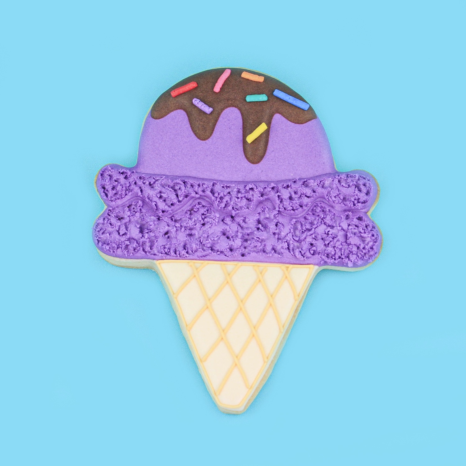 Double scoop of purple icecream with a chocolate drip and sprinkles in waffle cone decorated sugar cookie in royal icing.