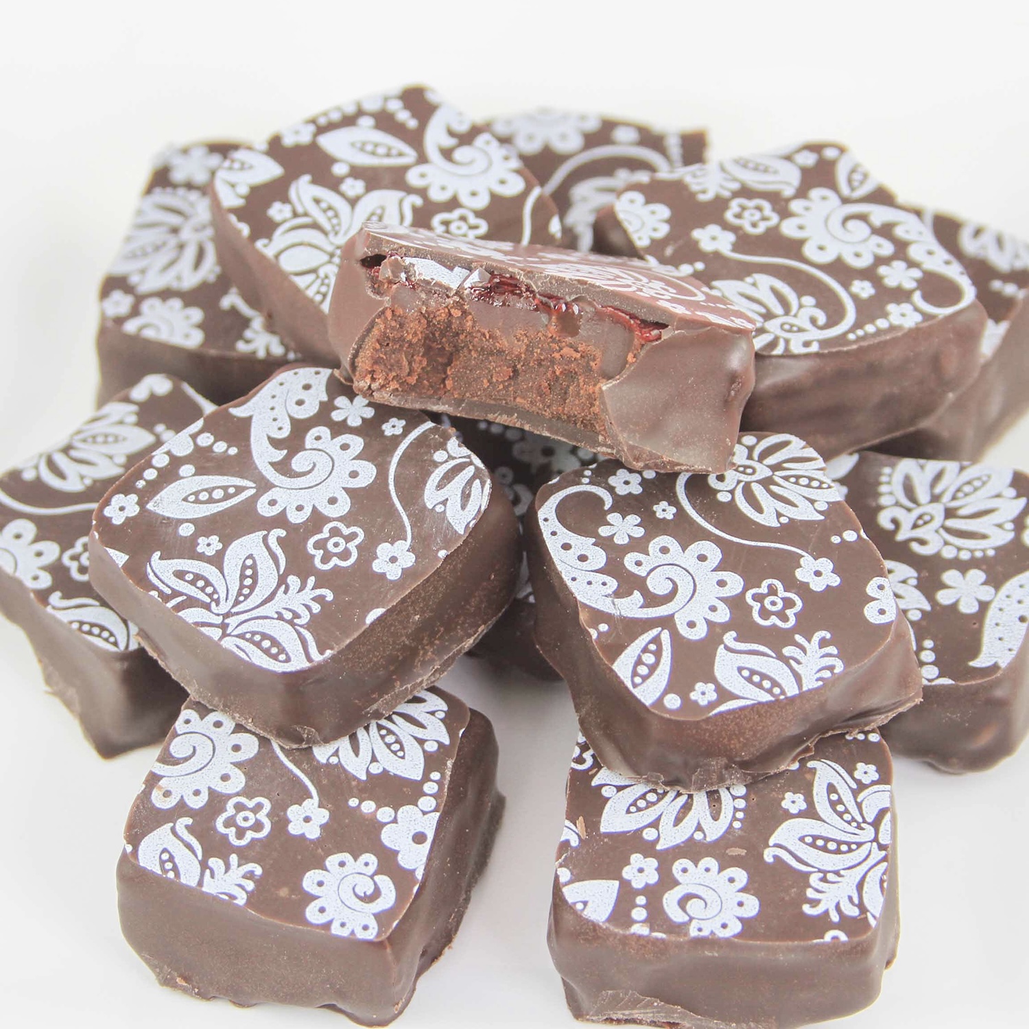 Dipped raspberry ganache squares imprinted with chocolate transfer sheet with a floral lilly pattern