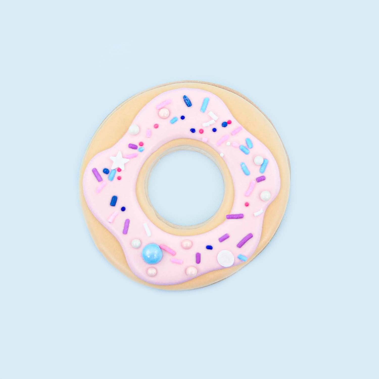 Donut decorated sugar cookie with pink royal icing and sprinkles.