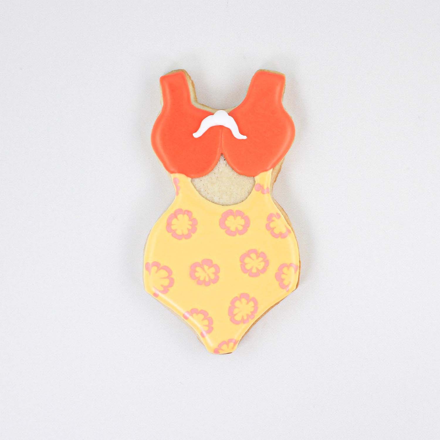 Bathing Suit cookie decorated in red and yellow with a pink flower patterned royal icing with a white bow.