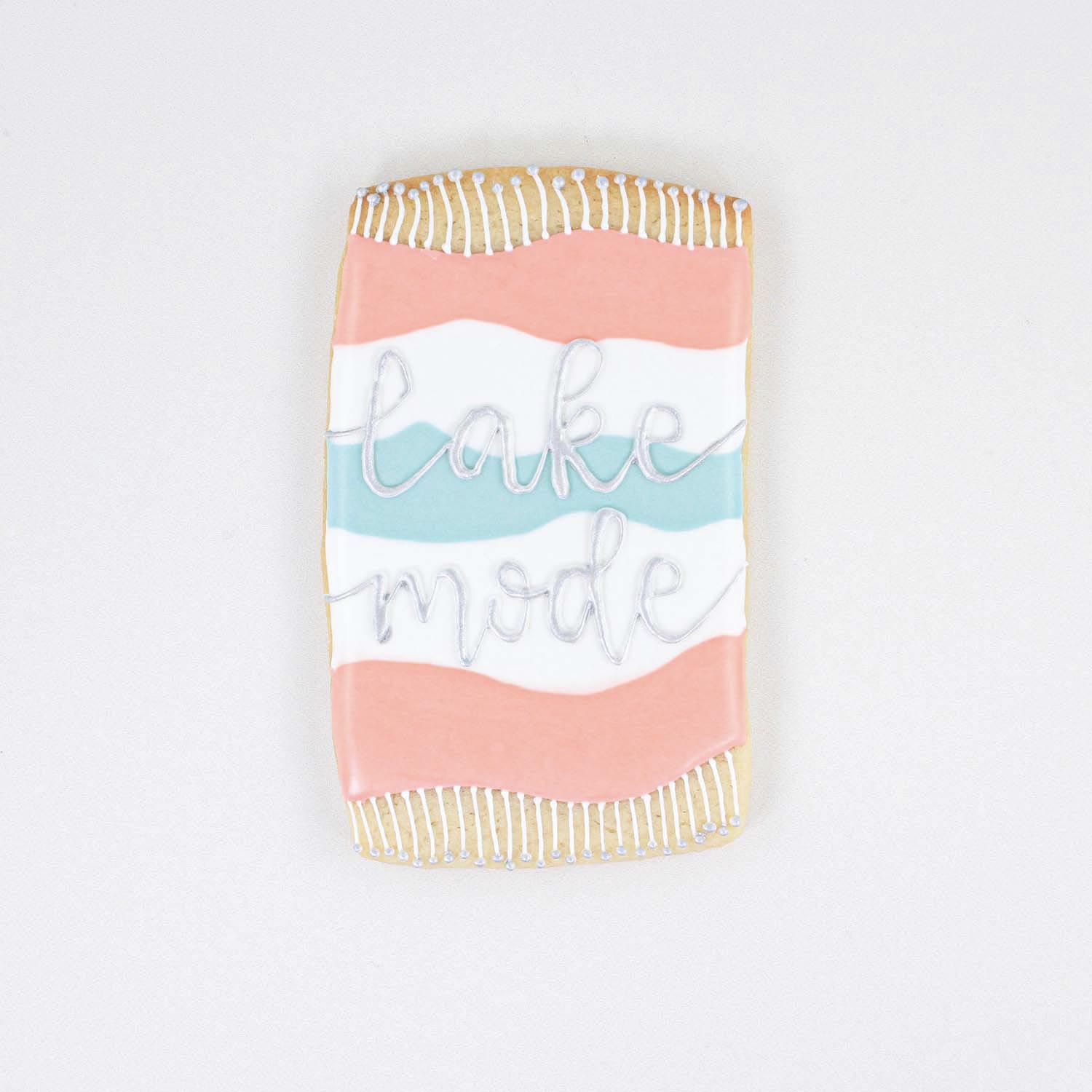 Beach towel decorated in royal icing colors of blue, white and pink and lake mode painted in silver edible paint.