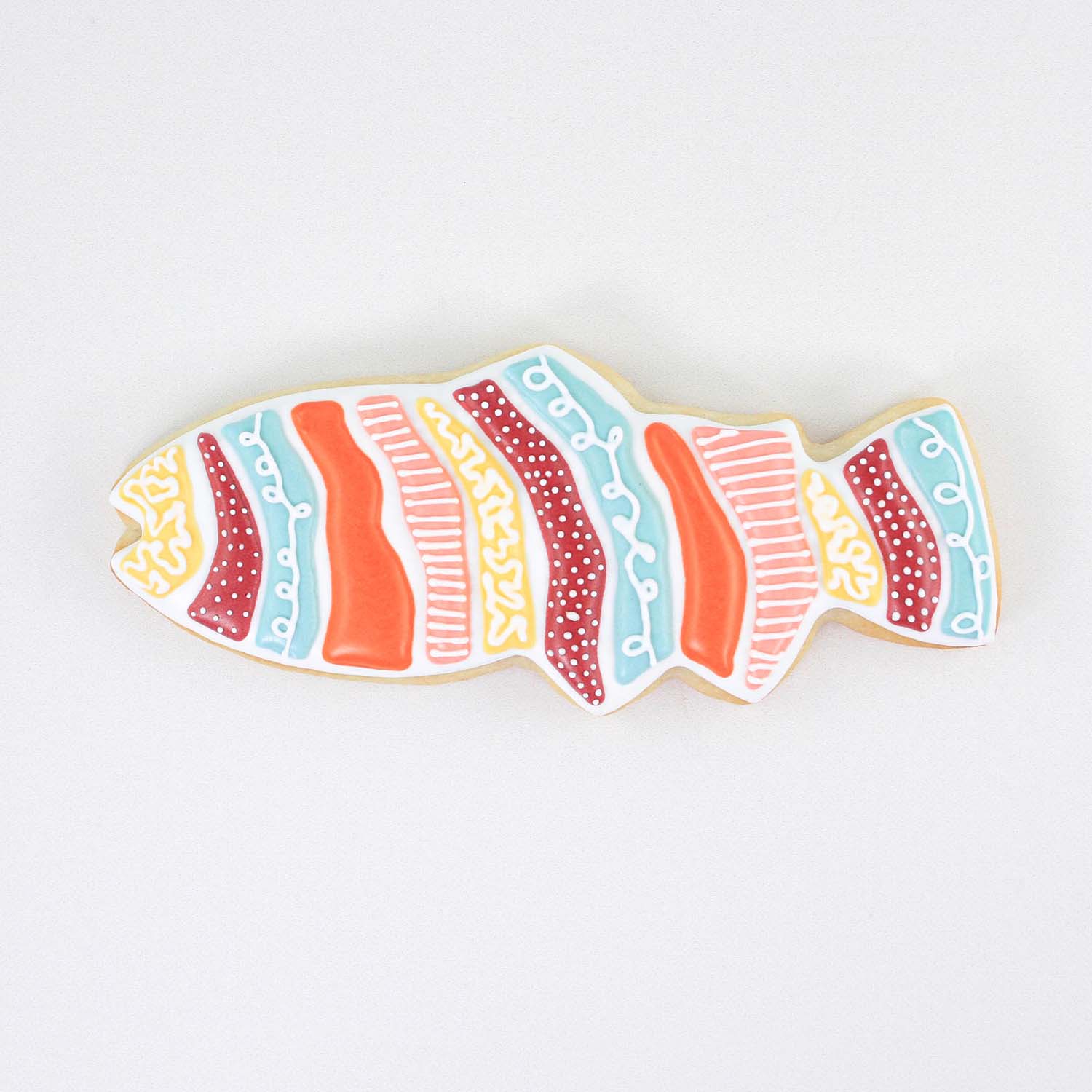 Bright color royal icing fish in red, white, blue, orange and yellow adorned stipes.