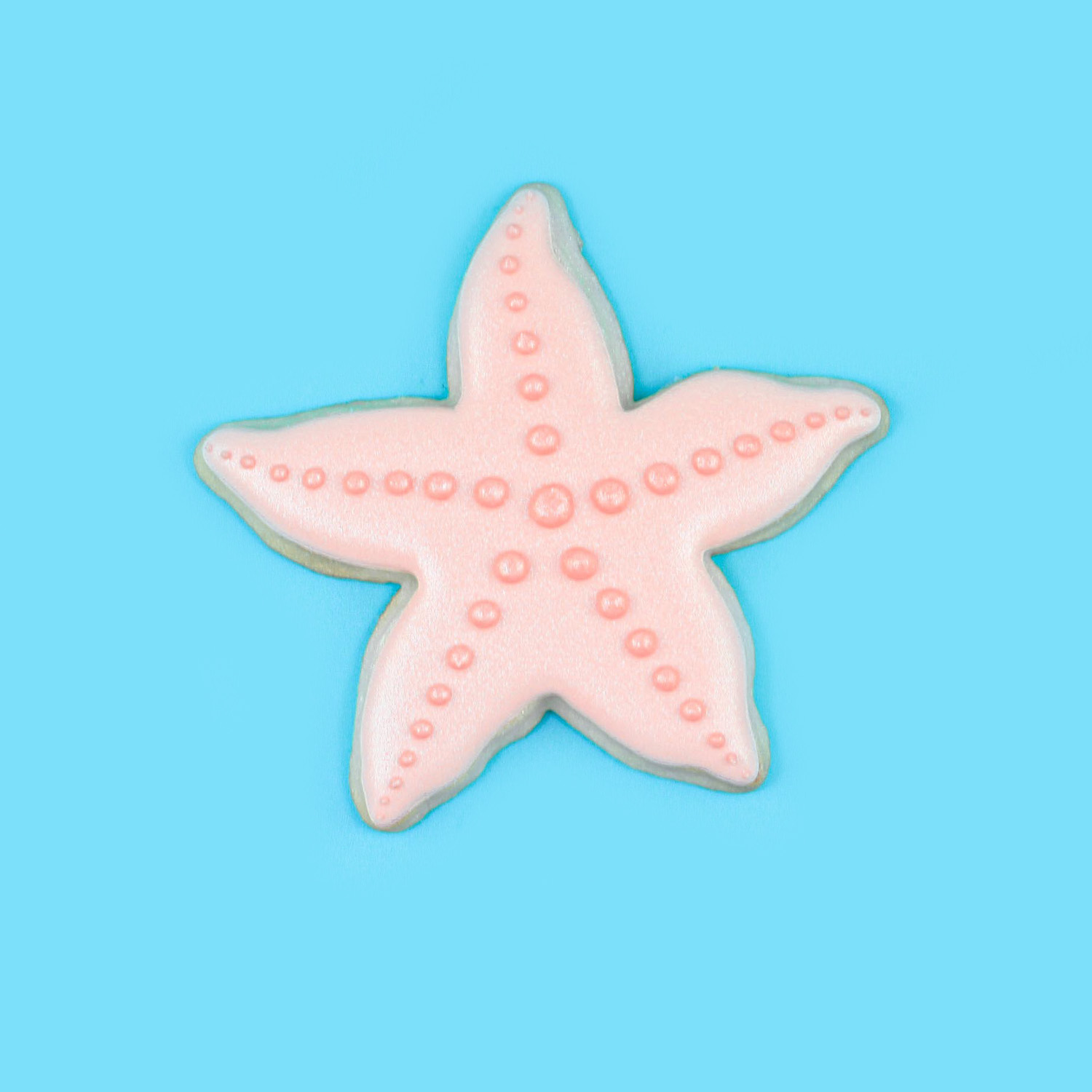 Starfish cookie decorated in light pink royal icing and dusted with rose gold shimmer.