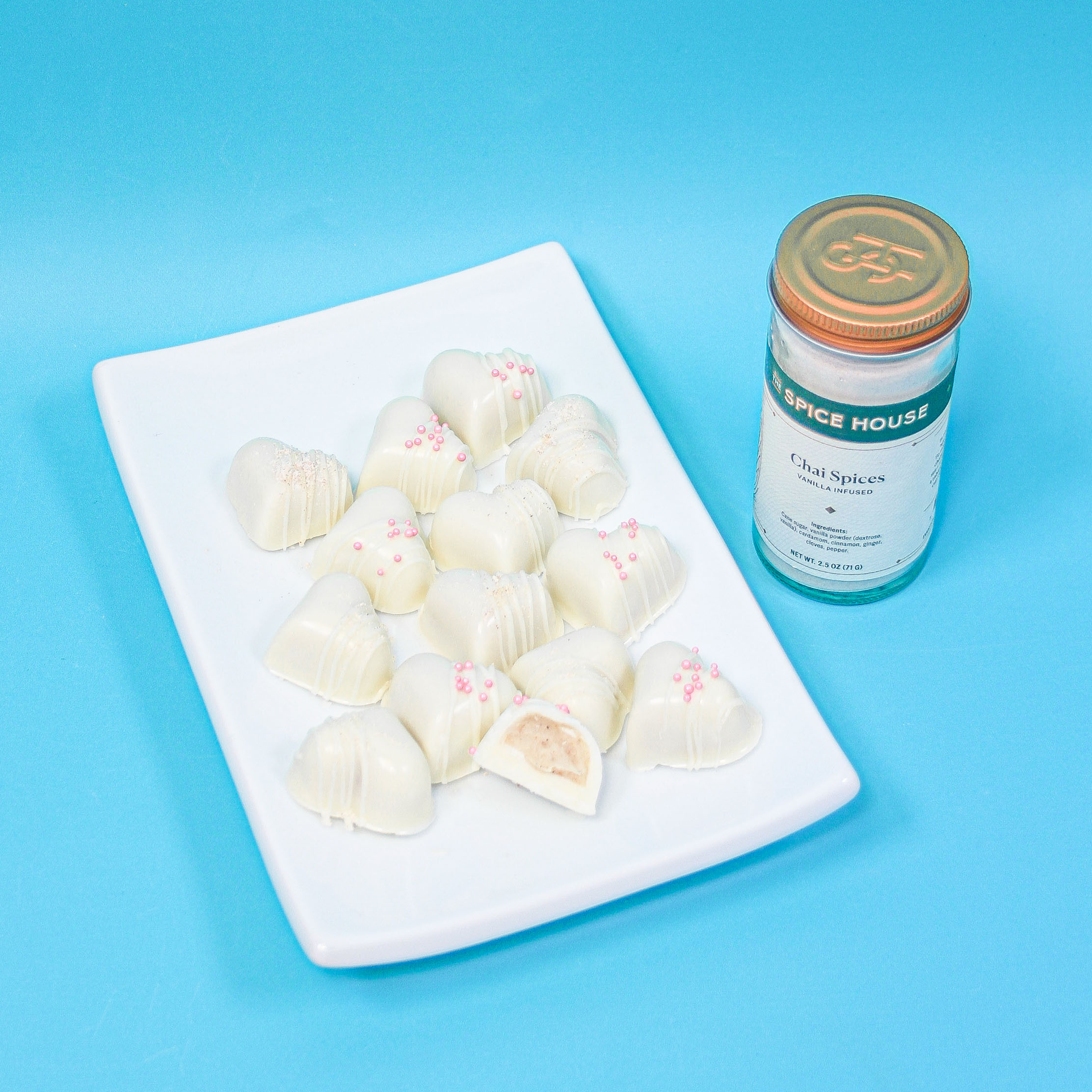 heart shaped chai turffles with white drizzle and pink nonpareils with a bottle of our vanilla infused chai spice.