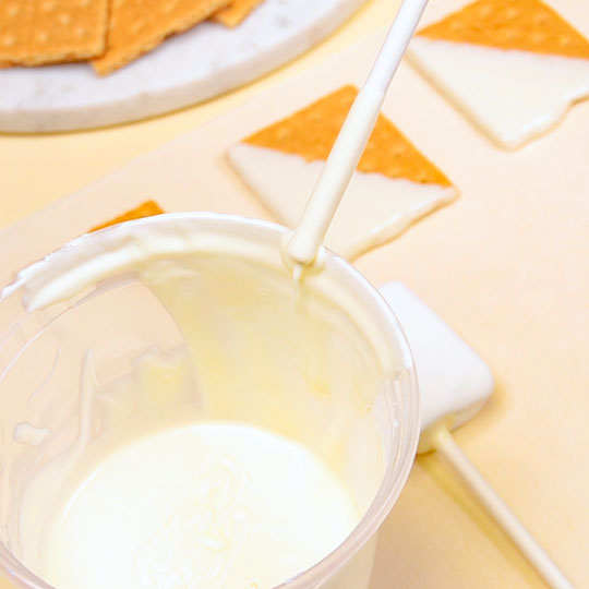 dipping cake pop stick in melted white chocolate