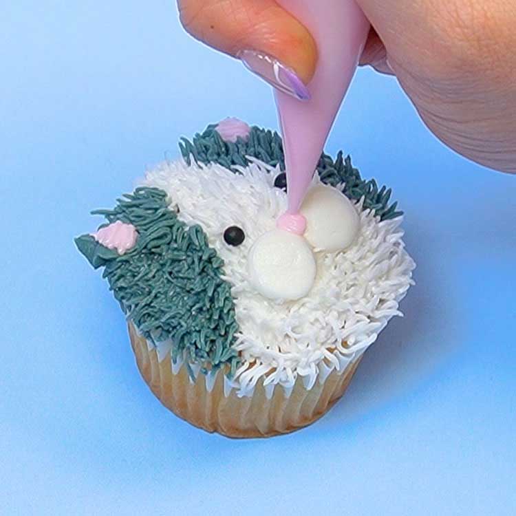 piping pink nose onto kitten cupcake