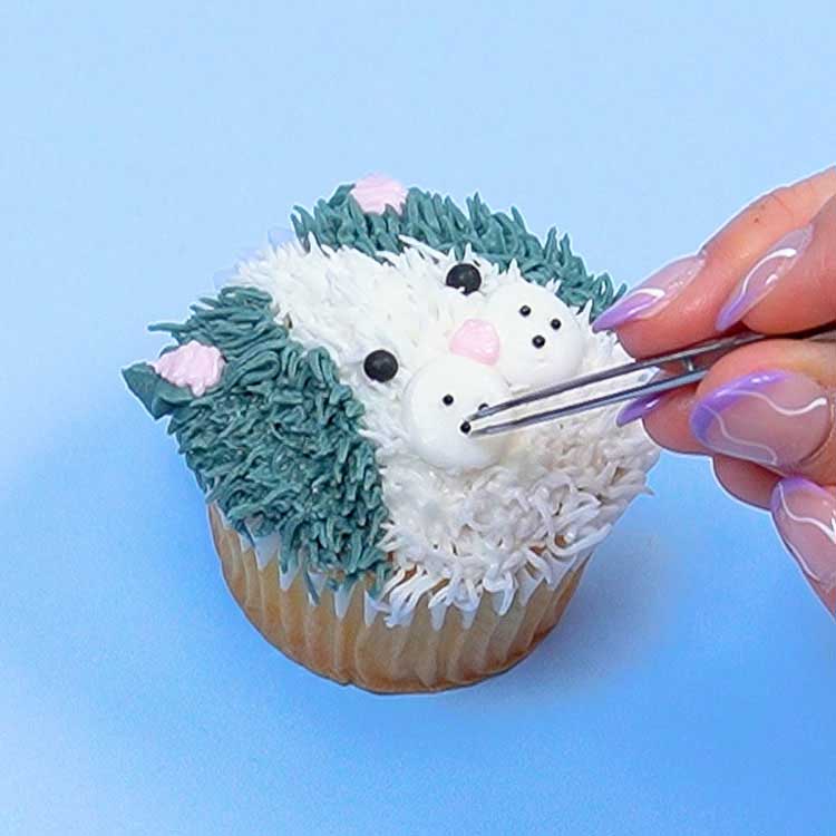 adding sprinkle whiskers onto kitten cupcake