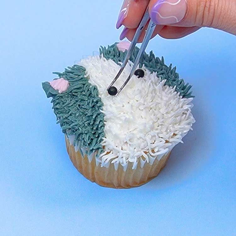 adding sprinkle eyes to make a kitten cupcake