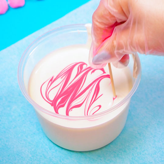 using a skewer to marble colour mill into white chocolate