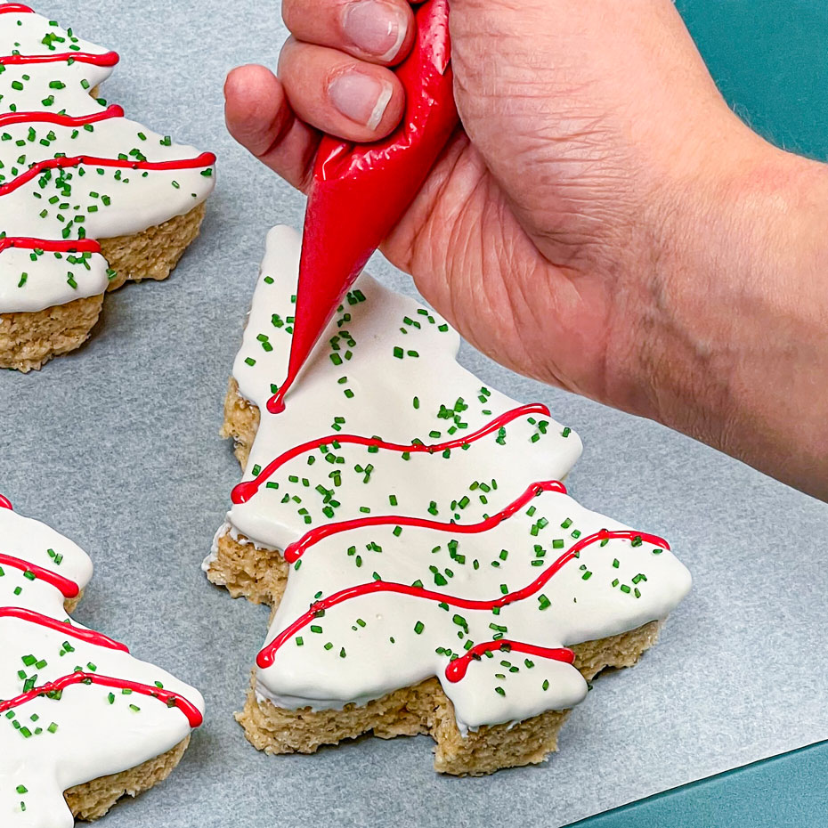 piping red chocolate onto christmas tree dessert