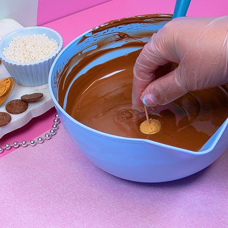 dipping buckeye into melted milk chocolate