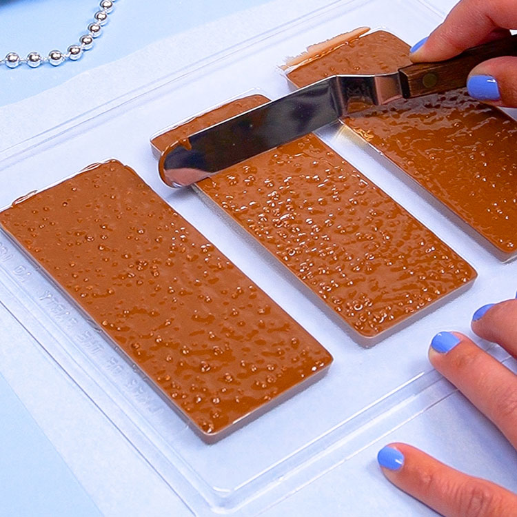 scraping away excess chocolate from mold