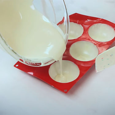 silicone hemisphere chocolate mold being filled with 2nd layer melted chocolate