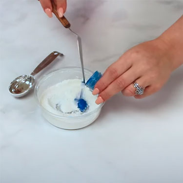 adding blue powdered food coloring to white hot chocolate mix