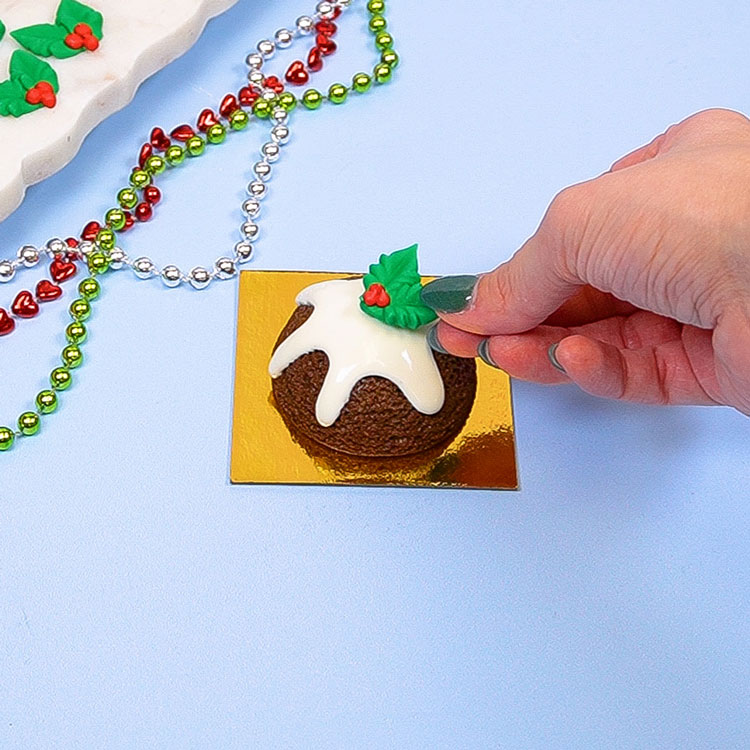 adding edible holly decoration to mini gingerbread cake