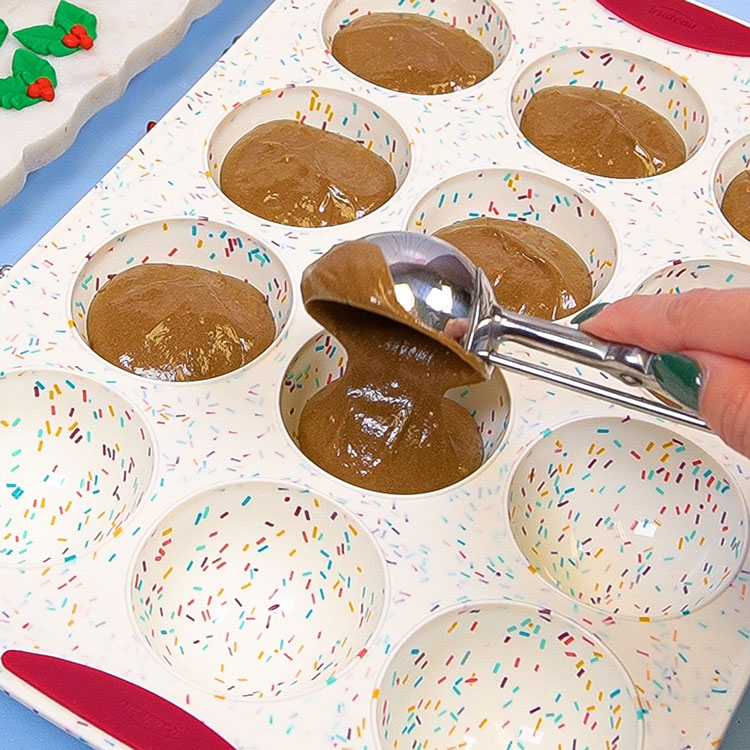 scooping gingerbread cake batter into hemisphere pan