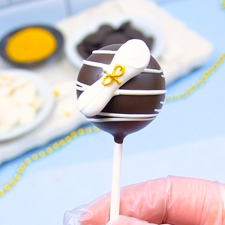 adding a royal icing diploma to cake pop