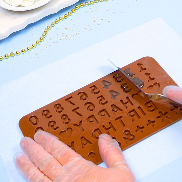 scraping away excess chocolate from silicone mold