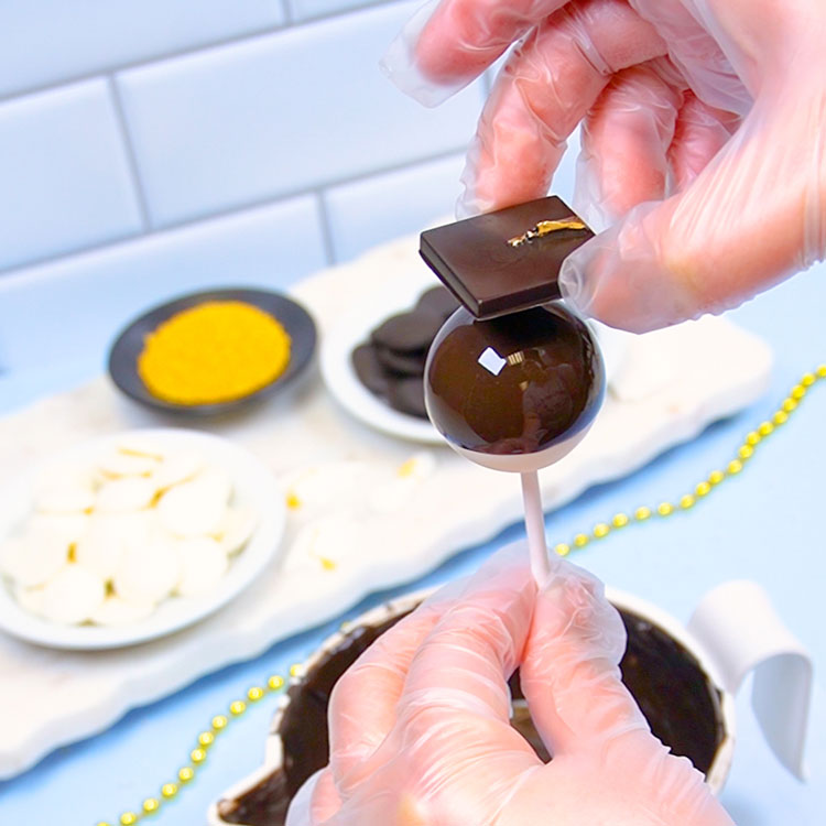 adding chocolate graduation cap to cake pop