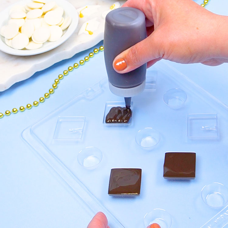 filling graduation cap chocolate mold with melted black chocolate