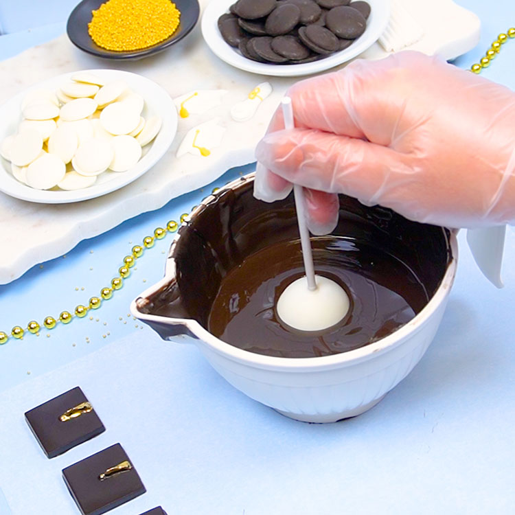 dipping cake pop into melted black chocolate