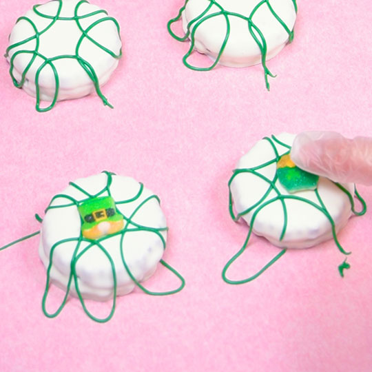 placing sugar decoration onto chocolate dipped sandwich cookie