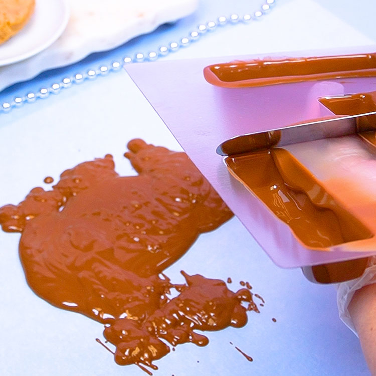 removing excess chocolate from mold using angled spatula