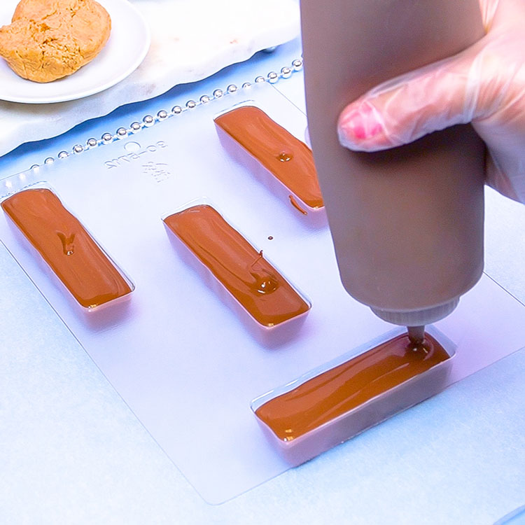 filling candy bar mold with melted milk chocolate