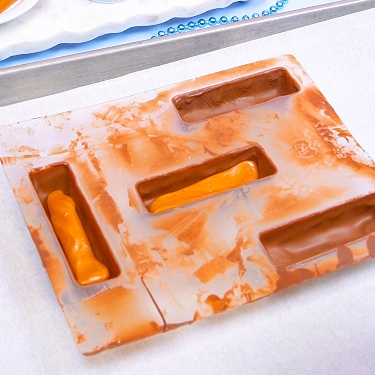 adding a layer of caramel to chocolate mold