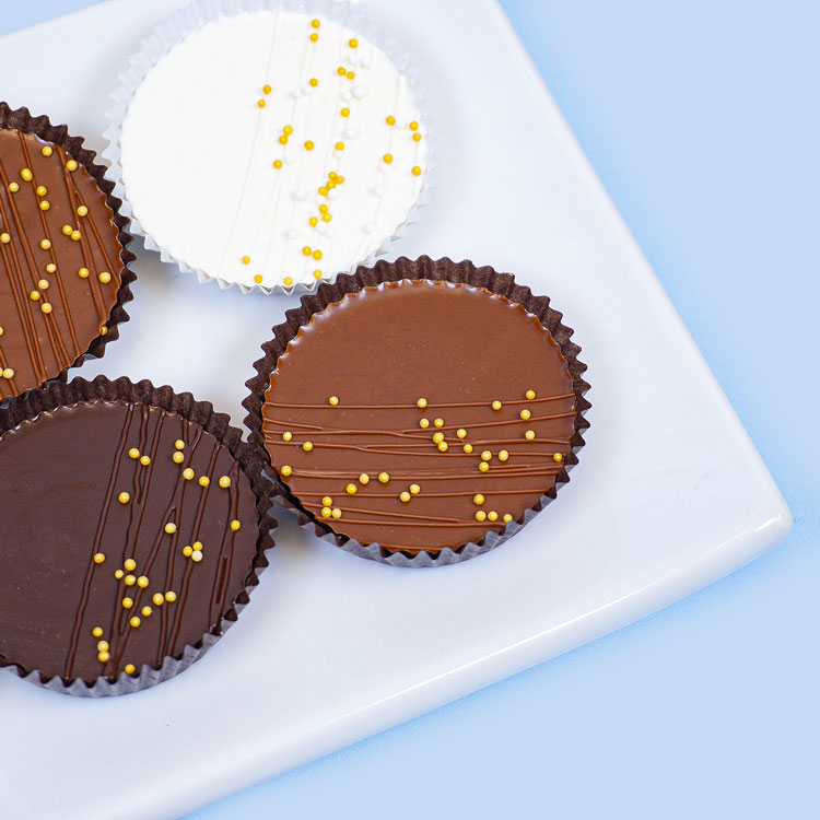 peanut butter cups decorated with a chocolate drizzle and gold sprinkles