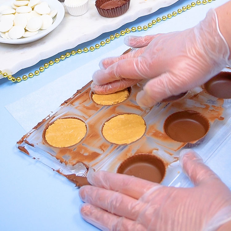 flattening peanut butter candy center with hands