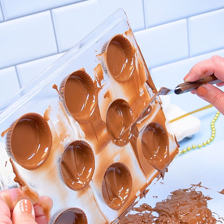 cleaning off the top of the chocolate mold with an angled spatula