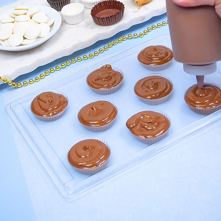 filling chocolate mold with a squeeze bottle filled with milk chocolate