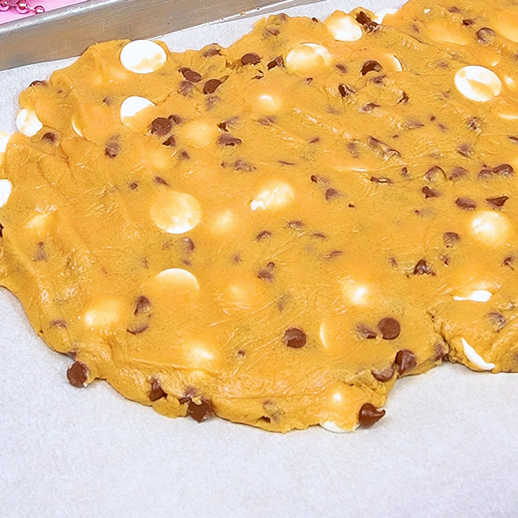 cookie dough spread on cookie sheet lined with parchment paper