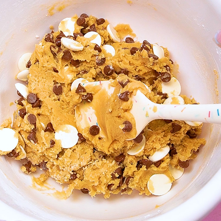 adding chocolate chips to cookie dough