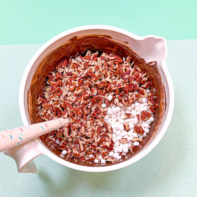 melted chocolate, pecan, and mini marshmallows mixed in a bowl