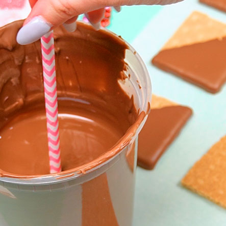 dipping straw into melted milk chocolate