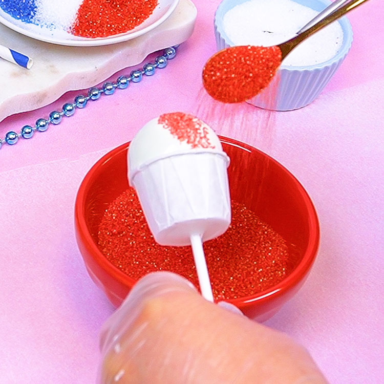 decorating snow cone cake pop with red sanding sugar